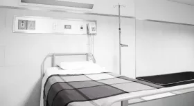 Empty hospital bed in sparse hospital room