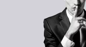 attorney-client privilege illustrated by man in business suit holding finger to his mouth