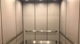 NYC elevator with white walls and stainless steel arm rails