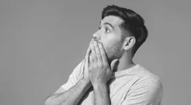 Man in t-shirt with hand over mouth