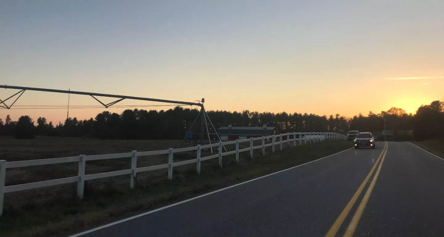 car driving at dusk on rural undivided road