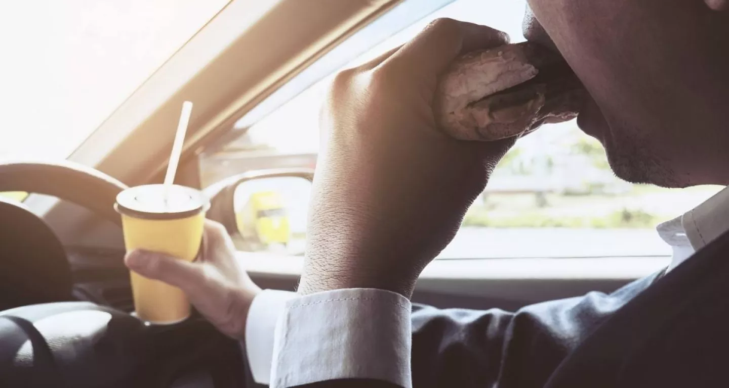 man distracted driving eating and drinking