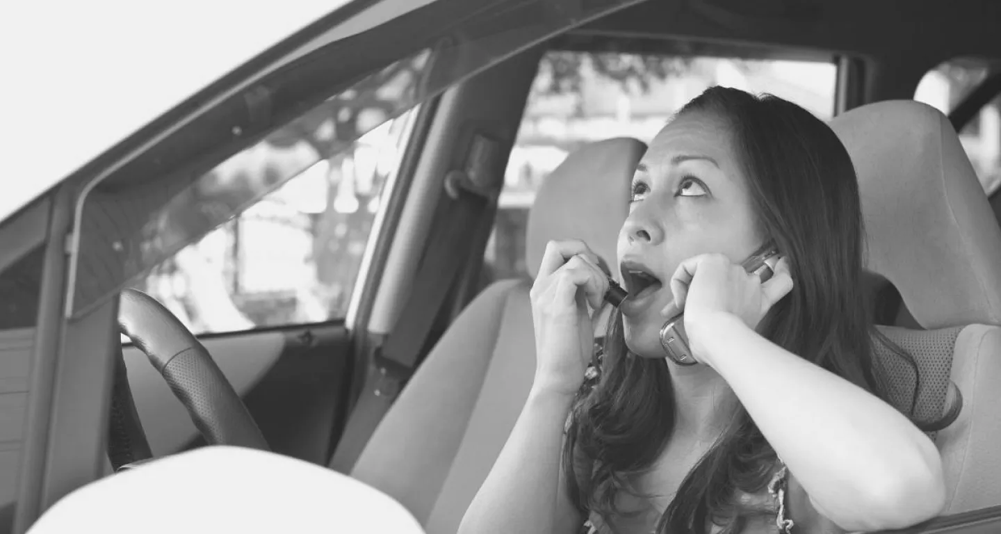 Negligent driver woman putting on lipstick talking on cell phone while driving