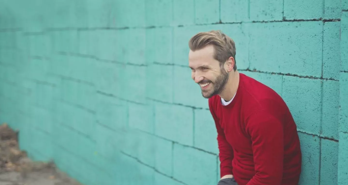 man leaning against wall smiling