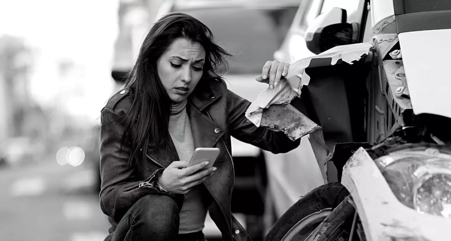woman looking at her phone worried about how to pay for a single vehicle accident in New York