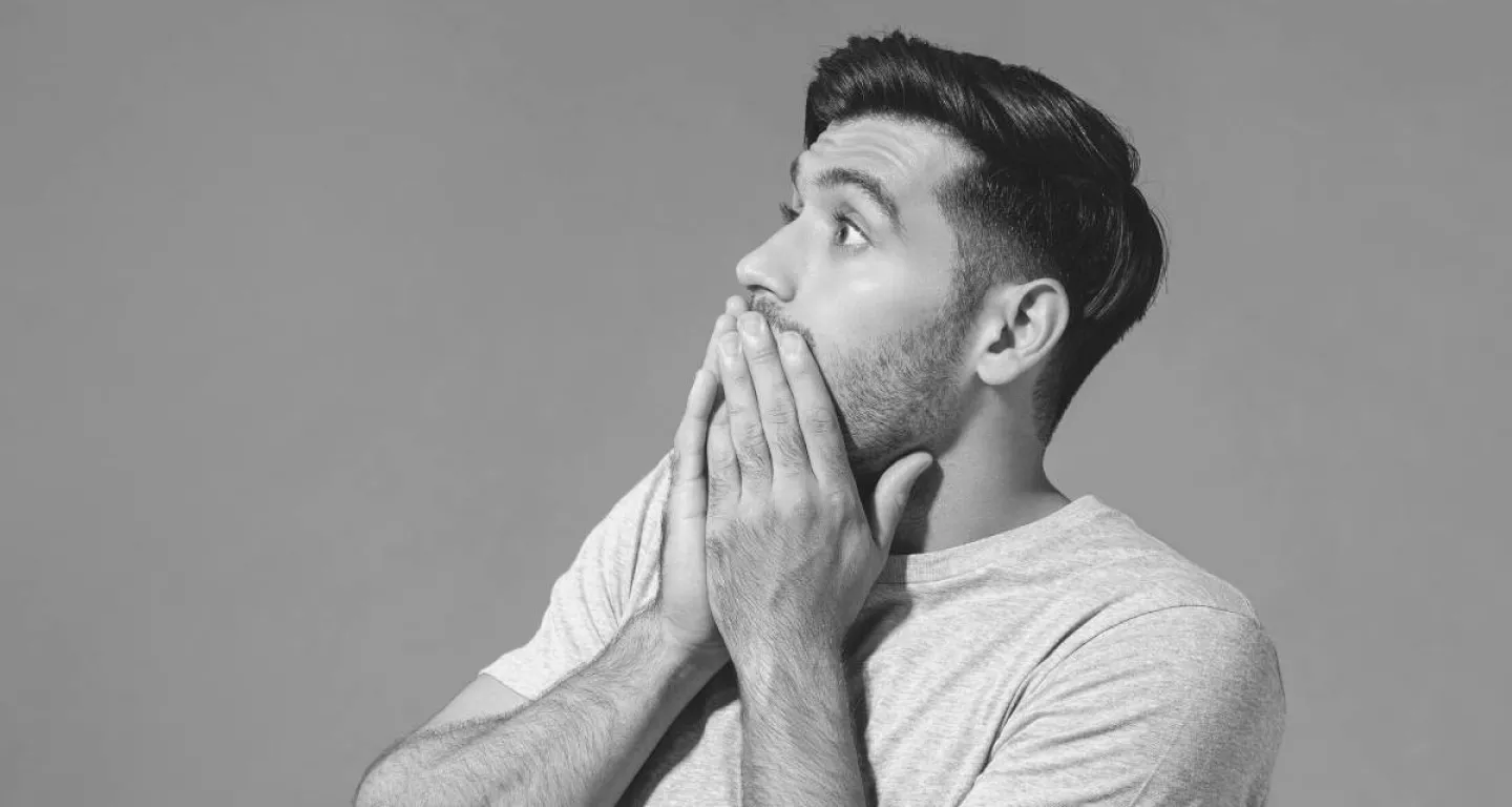 Man in t-shirt with hand over mouth